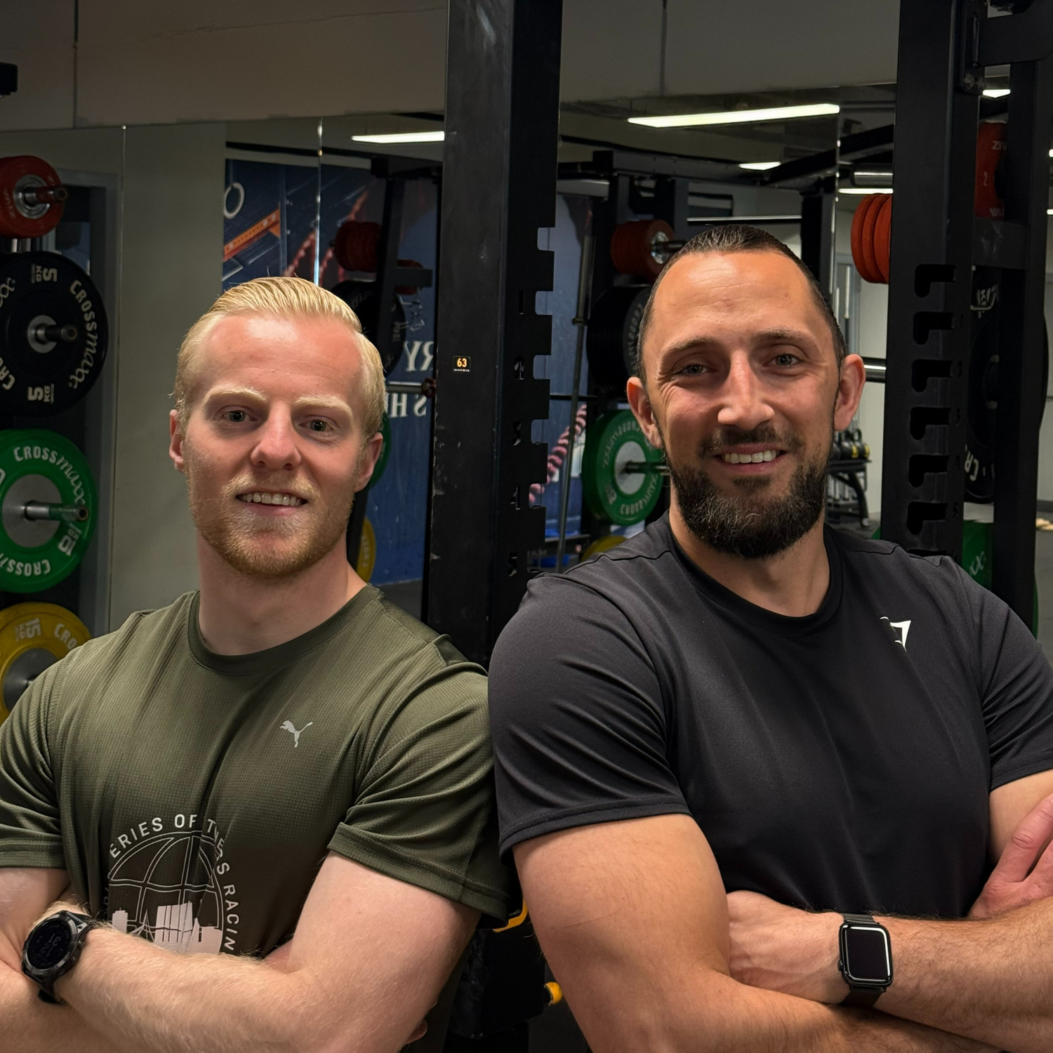 2 lachende mannen schouder tegen schouder in een sportruimte